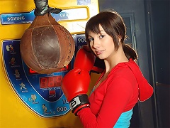 A young girl is posing in front of the camera wearing boxing gloves. She rubs herself all over, taking